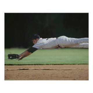 Baseball player in mid air catching ball. posters