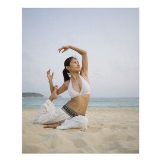Young woman doing yoga on the beach posters
