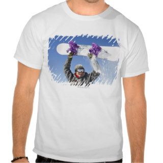 Young man holding his snowboard above his head shirts