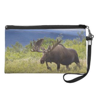 A large bull moose stands among willows wristlet purses